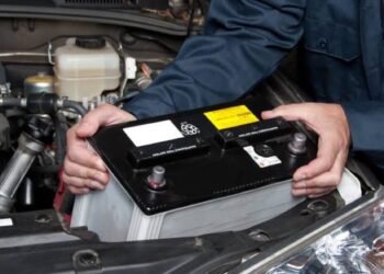 An image showing a man holding a car battery.